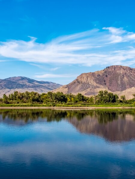 Thomson River, Kamloops, BC mit Bergkette und Eisenbahnbrücke in der Ferne. | © GettyImages.com/BriBar