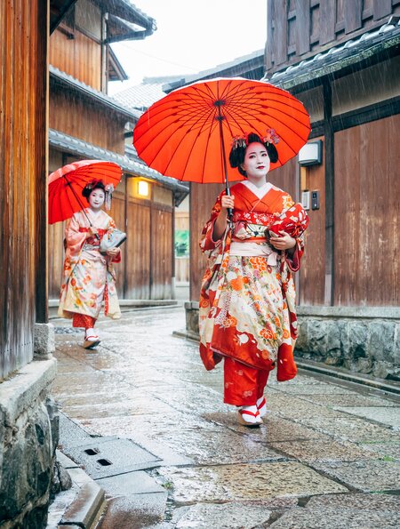 In Kimonos gekleidete Maiko Frauen laufen mit Schirmen durch den Regen  in Kyoto | © Gettyimages.com/FilippoBacci