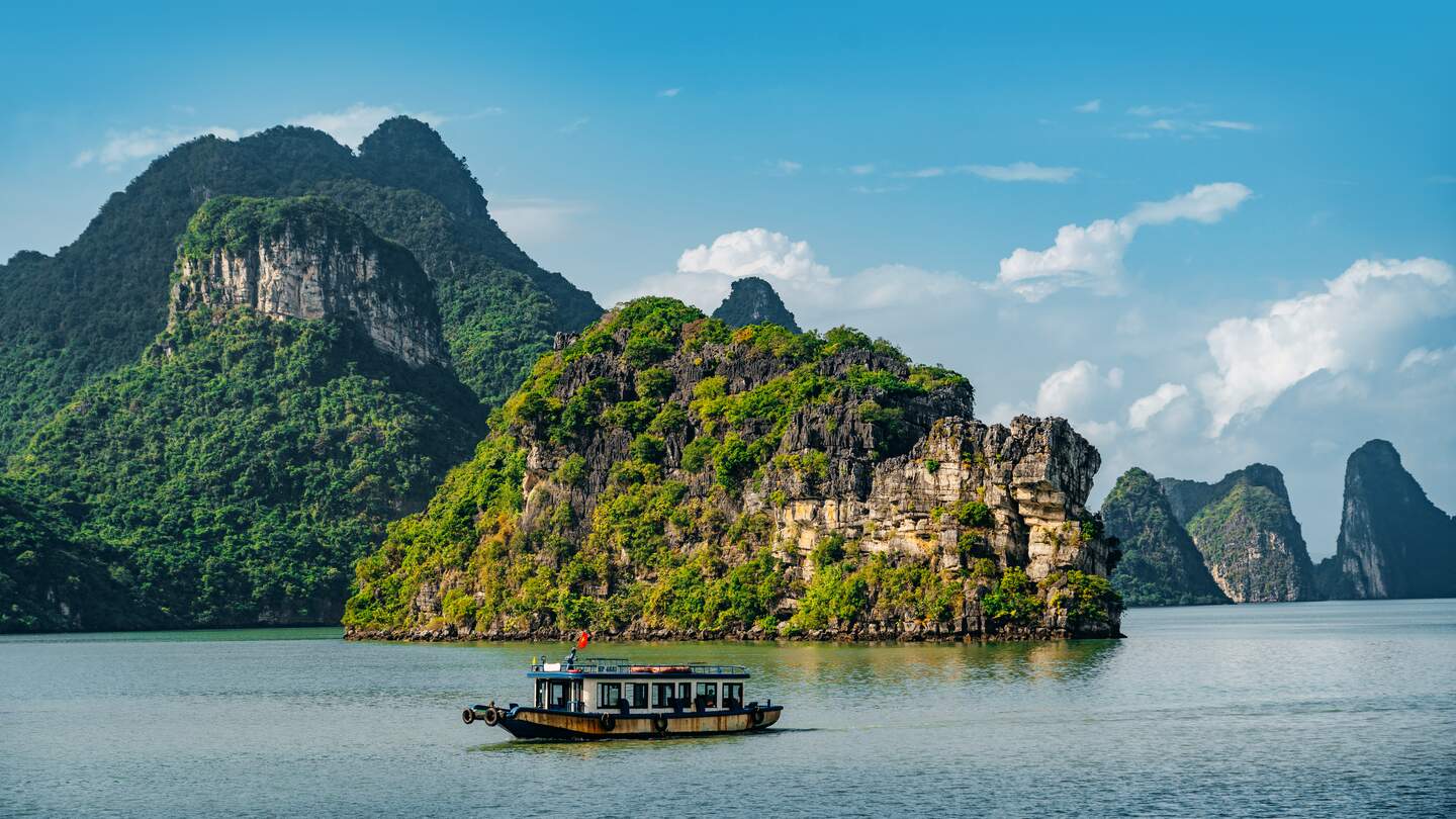 Die berühmte Halongbucht in Vietnam mit ihren hohen Kalksteinfelsen und einem Boot iin der Mitte | © GettyImages.com/Nikada