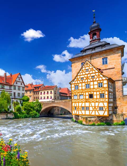 Blick auf das Rathaus und eine mit Blumen geschmueckte Bruecke in Bamberg | © Gettyimages.com/emicristea