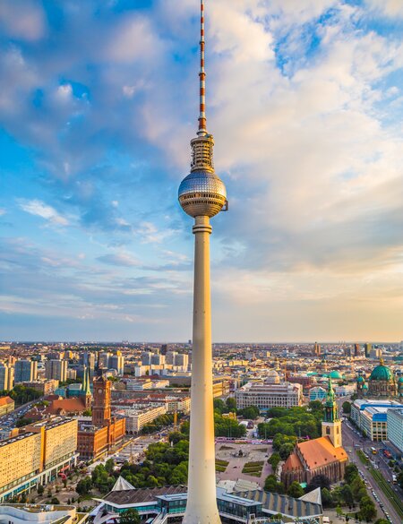 Weitwinkelansicht der Berliner Skyline mit beruehmtem Fernsehturm am Alexanderplatz und dramatischen Wolken im wunderschönen goldenen Abendlicht bei Sonnenuntergang im Sommer | © Gettyimages.com/bluejayphoto