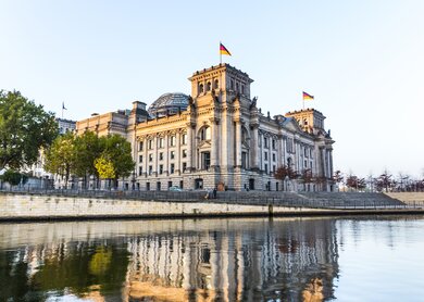 Das Reichstagsgebaeude in Berlin mit Spiegelung in der Spree am fruehen Morgen | © Gettyimages.com/Meinzahn