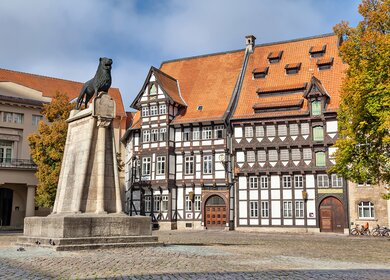 Statue von Leon und altes Fachwerkgebäude auf dem Burgplatz in Braunschweig | © GettyImages.com/bbsferrari