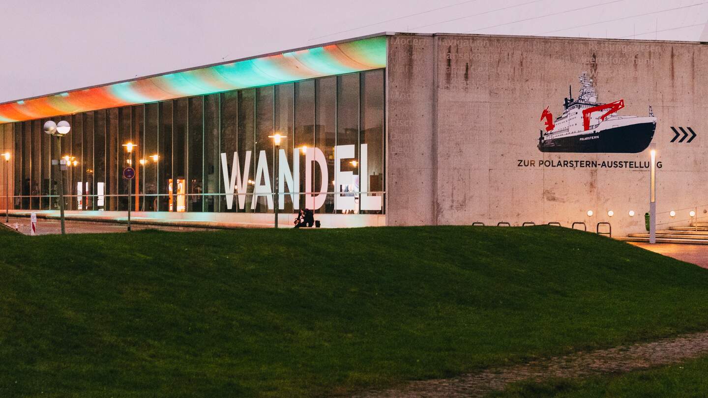 Das Schifffahrtsmuseum in Bremerhaven mit farbenfroher Beleuchtung und dem deutschen Wort fuer „Wandel“ | © Gettyimages.com/Wirestock