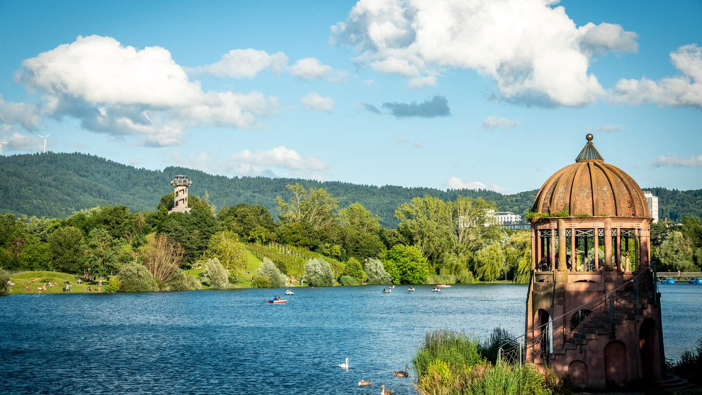 Buntes Panorama des Flueckiger Sees mit zwei Aussichtstuermen am Seepark in Freiburg | © GettyImages.com/Andreas Naegeli