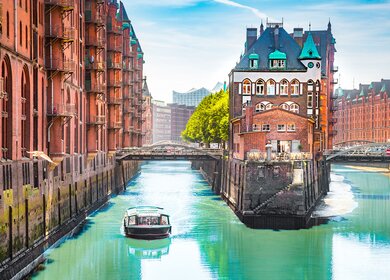Speicherstadt in Hamburg mit einem Tourboot auf dem Wasser | © Gettyimages.com/bluejayphoto