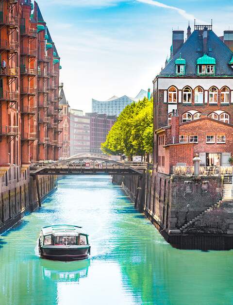 Speicherstadt in Hamburg mit einem Tourboot auf dem Wasser | © Gettyimages.com/bluejayphoto