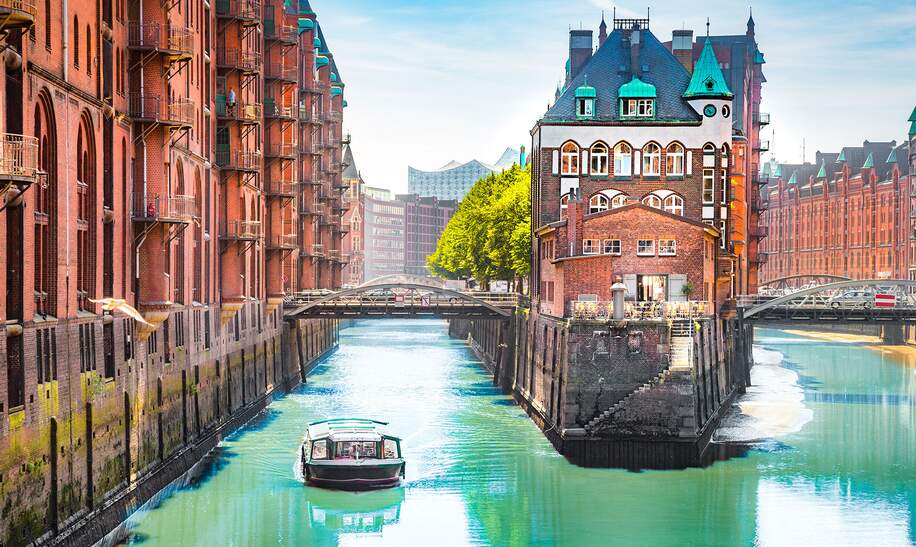 Speicherstadt in Hamburg mit einem Tourboot auf dem Wasser | © Gettyimages.com/bluejayphoto