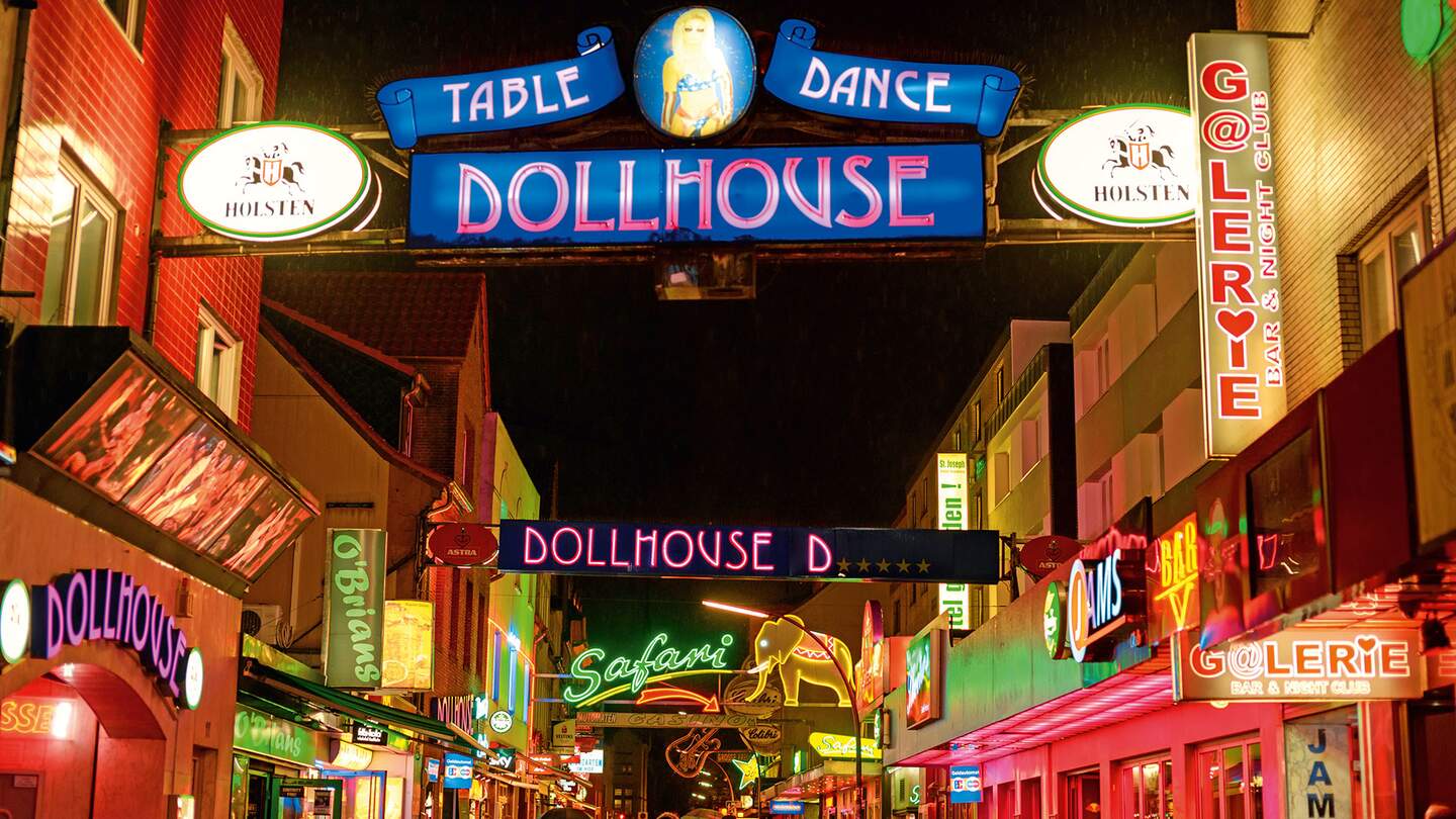 Reeperbahn Hamburg bei Nacht mit leuchtenden Schildern. Im Vordergrund ist Dollhouse zu lesen. | © Gettyimages.com/Juergen Sack