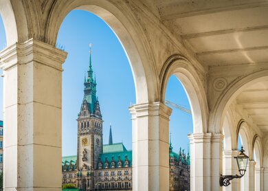 Gewoelbe ueber den Restaurants und Strassencafés der Alsterarkaden, ueberragt von der ikonischen Spitze des Rathauses im Herzen von Hamburg, Deutschland. | © Gettyimages.com/fotoVoyger