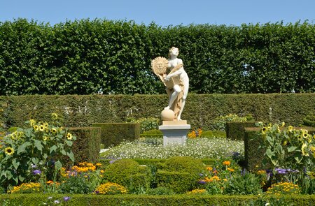 Statue der Sonnengöttin in den Koeniglichen Gaerten von Hannover in Herrenhausen mit bluehenden Blumen | © Gettyimages.com/villy_yovcheva
