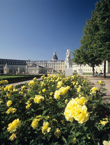 Schloss Karlsruhe mit gelben Rosen im Vordergrund und blauem Himmel | © Gettyimages.com/rotofrank