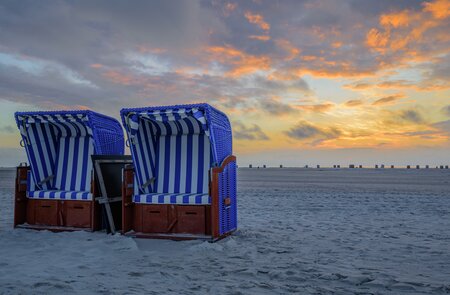 Zwei Strandsessel nebeneinander am weissen Sandstrand mit Sonnenuntergang Daemmerung im Himmel | © Gettyimages.com/frederickdoerschem