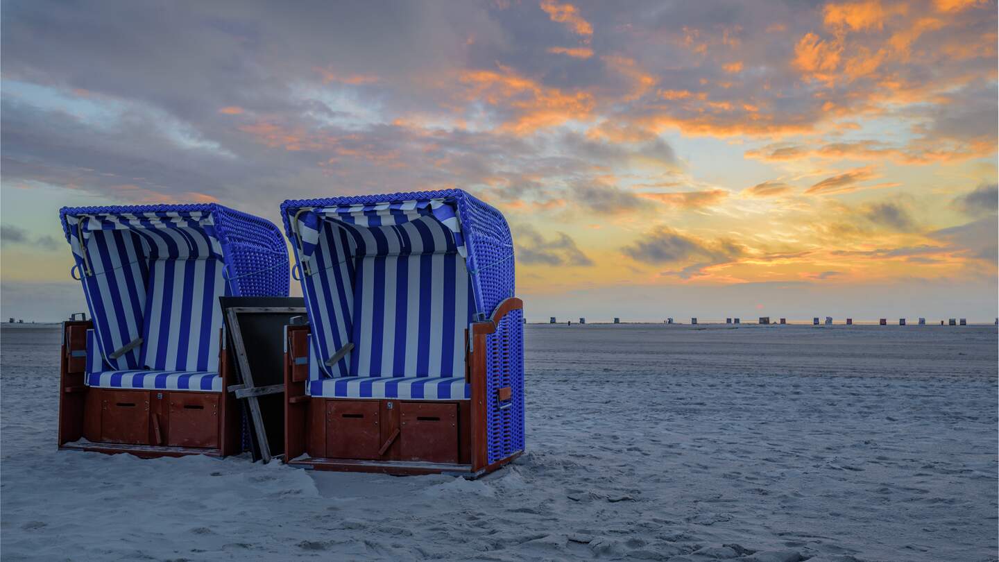 Zwei Strandsessel nebeneinander am weissen Sandstrand mit Sonnenuntergang Daemmerung im Himmel | © Gettyimages.com/frederickdoerschem