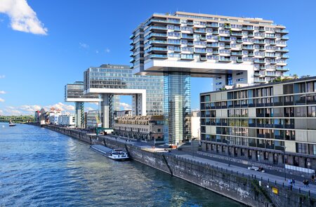 Das Kranhäuser-Trio an der Rheinpromenade in Köln, Menschen laufen auf der Promenade. | © Gettyimages.com/alxpin