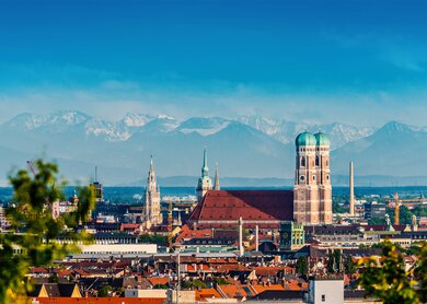 Die Skyline von München mit der Frauenkriche bei schönem Wetter mit Bergen im Hintergrund | © Gettyimages.com/jotily