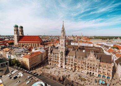  eine Luftaufnahme des Marienplatzes, dem zentralen Platz in Muenchen, mit dem Neuen Rathaus und seiner aufwendigen gotischen Fassade sowie den Zwillingstuermen der Frauenkirche im Hintergrund. | ©  Gettyimages.com/Nikada