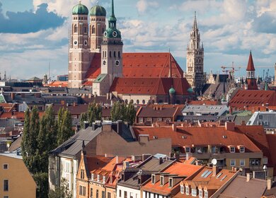 Stadtueberblick von München mit Frauenkirche und Rathaus bei bewoelktem Wetter | © Gettyimages.com/ShuraveyArt