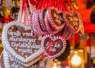 Mehrere Lebkuchenherzen an einem Stand mit der Aufschrift, Hab dich lieb oder Gruss vom Nuernberger Christkindlesmarkt | © Gettyimages.com/pusteflower9024