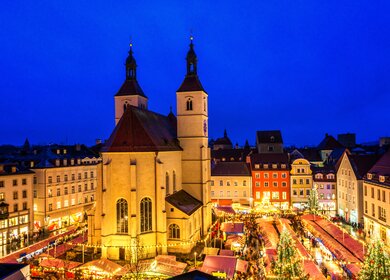 Erhoehter Blick auf den Regensburger Weihnachtsmarkt mit Essens- und Weihnachtsdekorationsstaenden rund um die 500 Jahre alte Neupfarrer Kirche und schönen Haeusern. | © Gettyimages.com/Juergen Sack