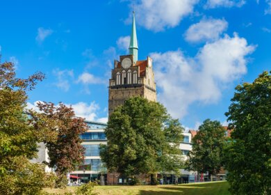 Blick auf das Kroepeliner Tor in Rostock mit einem Park im Vordergrund | © Gettyimages.com/RicoK69