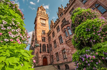 Untersicht auf das Rathausgebaeude in der Saarbruecken, Saarland, das Touristische und Reise-Wahrzeichen im Fruehling mit Blumen | © Gettyimages.com/frantic00