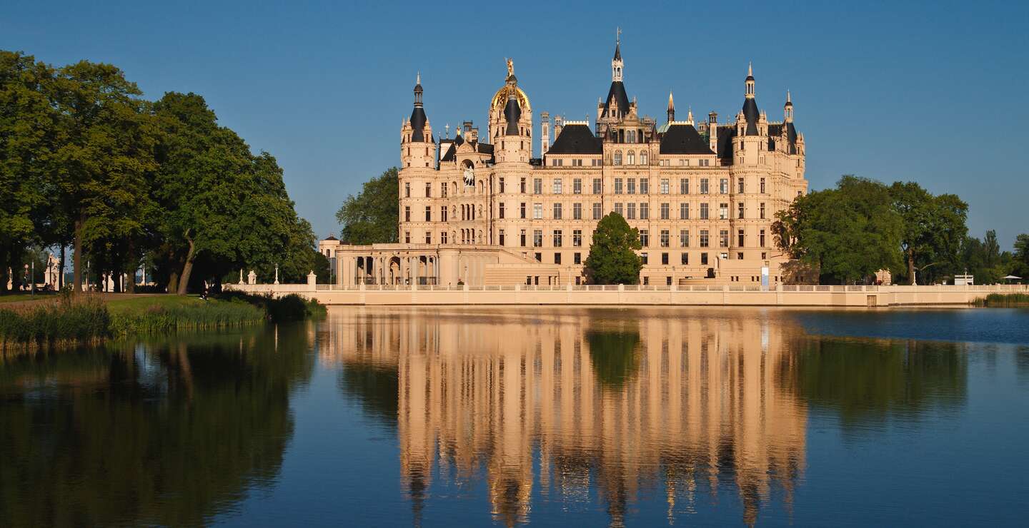  Schloss mit vielen Tuermen und Verzierungen, das sich malerisch im ruhigen Wasser spiegelt. | © gettyImages.com/RicoK69