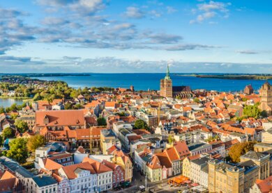 Panoramablick von der Spitze der Altstadt von Stralsund im Sommer, im Hintergrund die Ostsee mit der Insel Ruegen. | © Gettyimages.com/a-tom