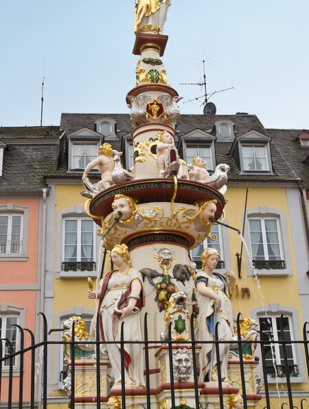 Untersicht auf den Petersbrunnen vor bunten Haeusern der Altstadt in Trier  | © Gettyimages.com/Elisabeth Schittenhelm