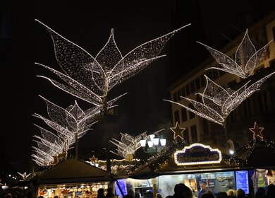 Haendler auf dem beleuchteten Weihnachtsmarkt in Wiesbaden bei Nacht | © Gettyimages.com/Mahmoud Mahdi
