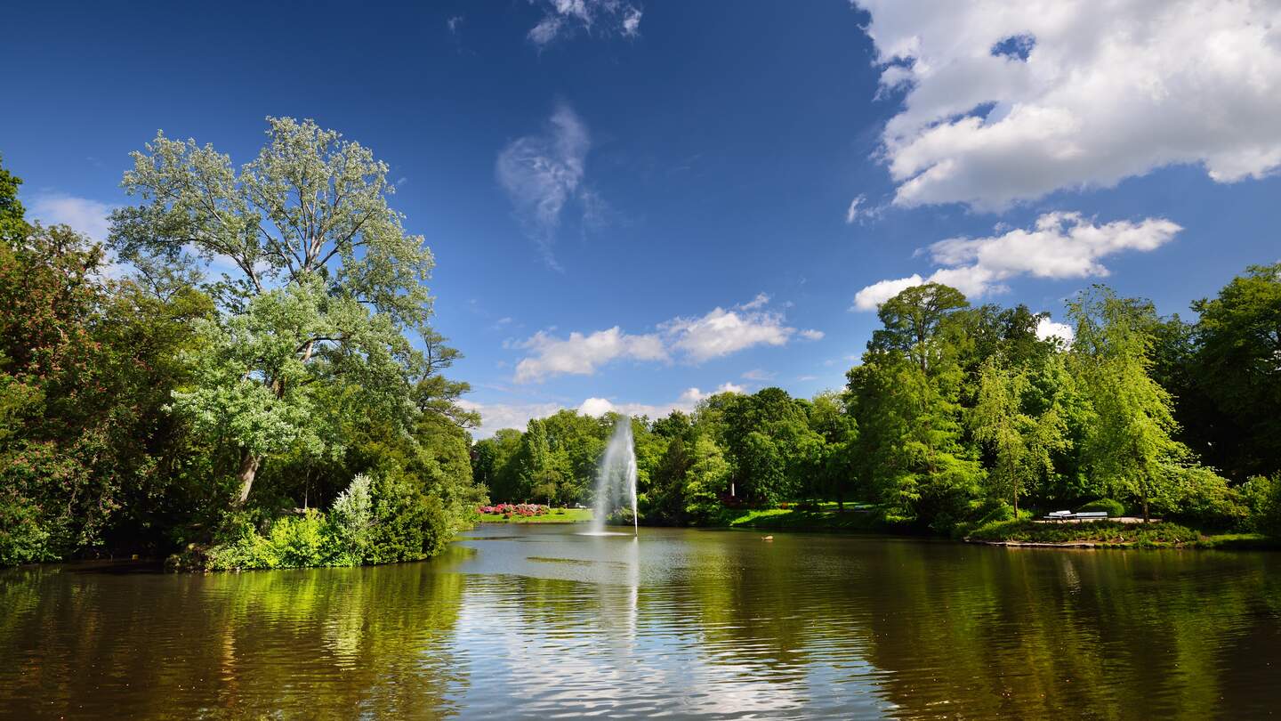 Blick auf einen schönen See mit Springbrunnen in einem grünen bluehenden Kurpark in Wiesbaden | © Gettyimages.com/alekseystemmer