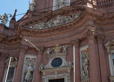 Untersicht auf den Neumuenster in Würzburg mit hellem Himmel | © Gettyimages.com/Anne Czichos