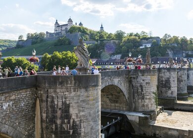 Blick auf die alte Mainbruecke in Wuerzburg mit Statuen und vielen Toristen bei gutem Wetter | © Gettyimages.com/omersukrugoksu