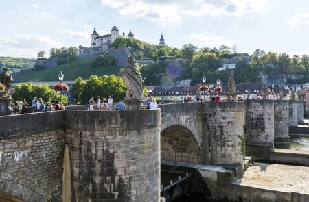 Blick auf die alte Mainbruecke in Wuerzburg mit Statuen und vielen Toristen bei gutem Wetter | © Gettyimages.com/omersukrugoksu