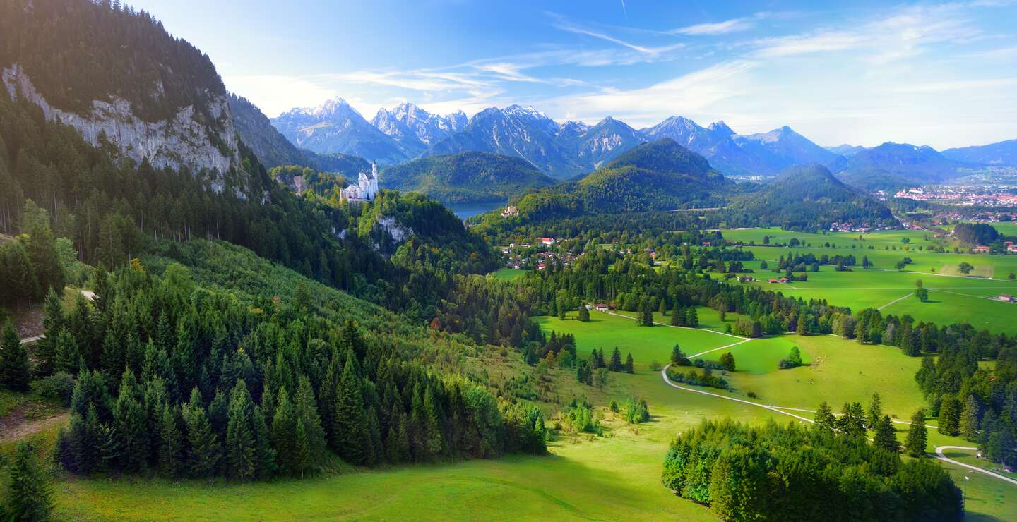 Beruehmtes Schloss Neuschwanstein sehen in der Ferne, liegt auf einem schroffen Huegel über dem Dorf Hohenschwangau im suedwestlichen Bayern | © Gettyimages.com/MNStudio