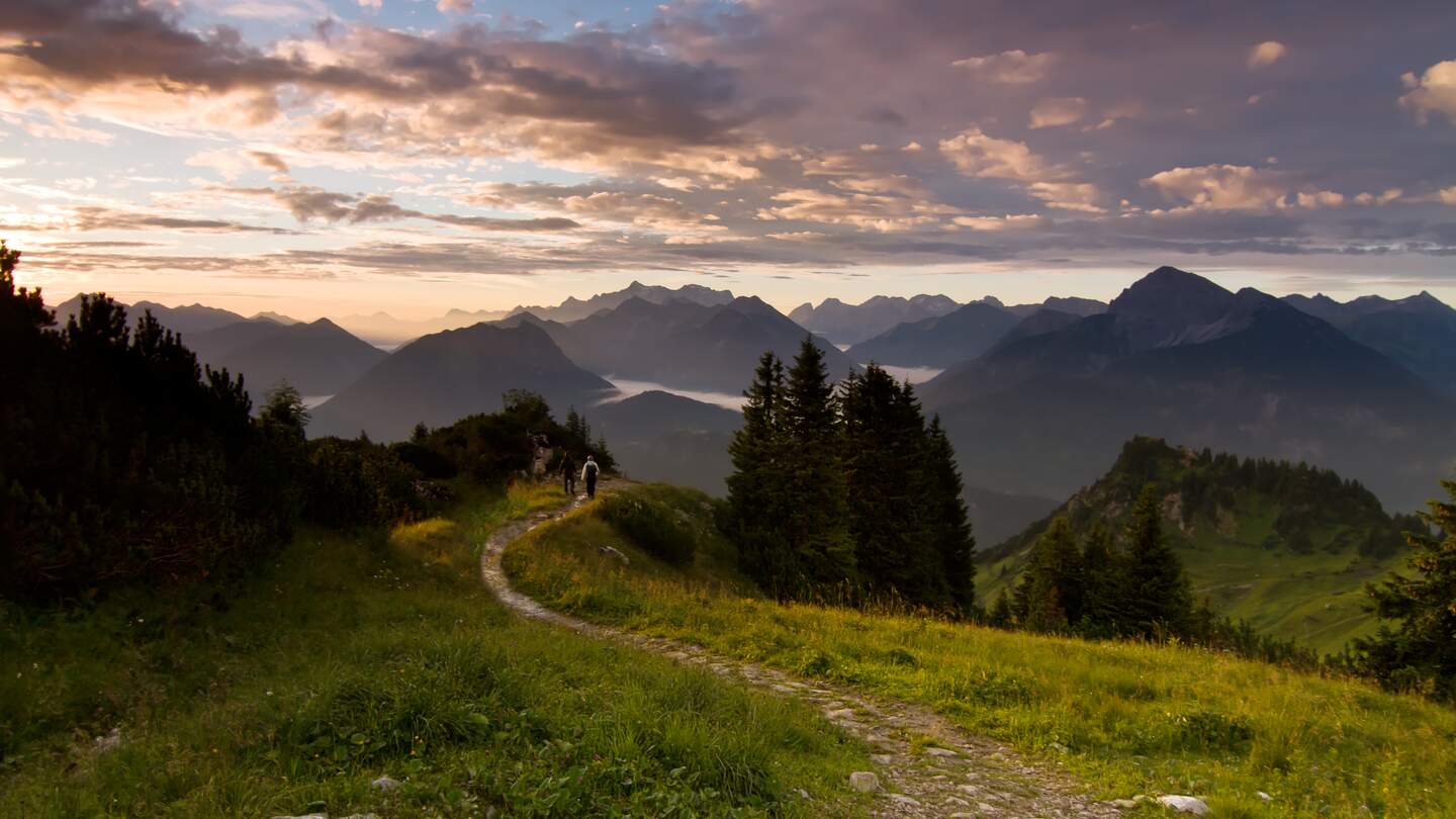 Zwei Wanderer laufen bei Sonnenuntergang auf einem Wanderweg im Bayerischen Wald. | © Gettyimages.com/landschaftsfoto