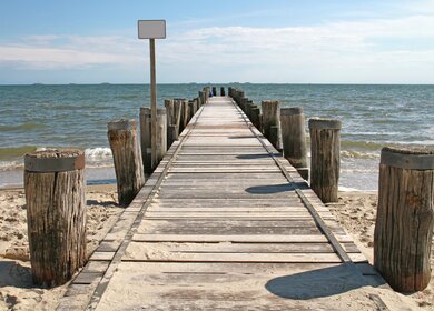 Hoelzerne Seebrücke auf Foehr mit Halligen im Hintergrund | © Gettyimages.com/Canetti