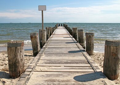 Hoelzerne Seebrücke auf Foehr mit Halligen im Hintergrund | © Gettyimages.com/Canetti