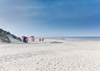 Strandkoerbe auf der Insel Borkum mit weissem Sand und ein blauer Himmel | © Gettyimages.com/tobiasschwarz