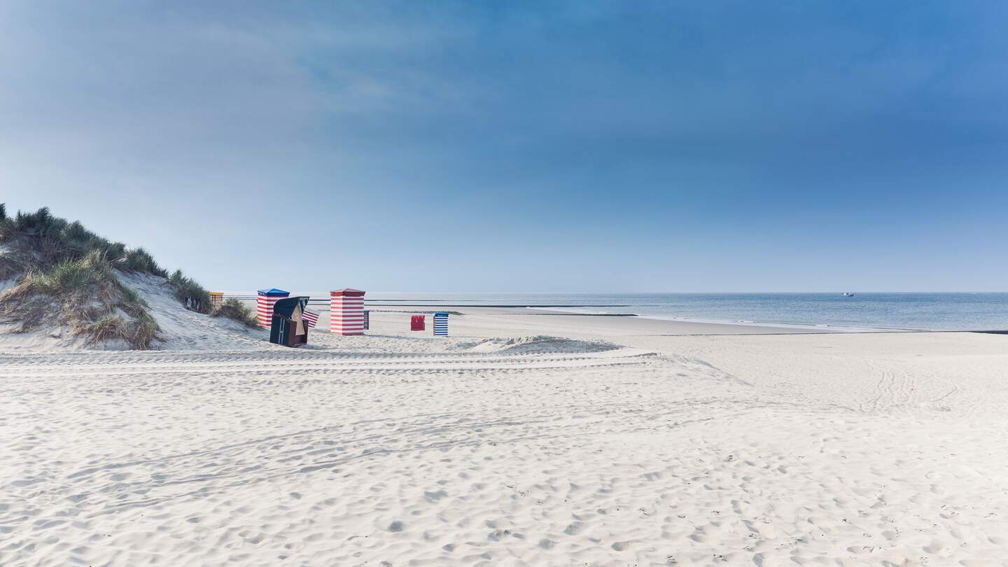 Strandkoerbe auf der Insel Borkum mit weissem Sand und ein blauer Himmel | © Gettyimages.com/tobiasschwarz