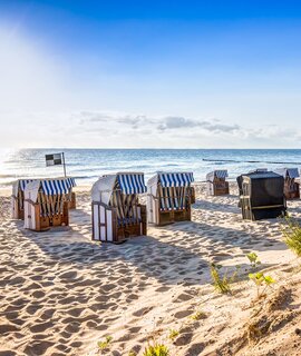  einen Sandstrand mit mehreren traditionellen Strandkoerben, die zum Meer hin ausgerichtet sind | ©  Gettyimages.com/mije_shots