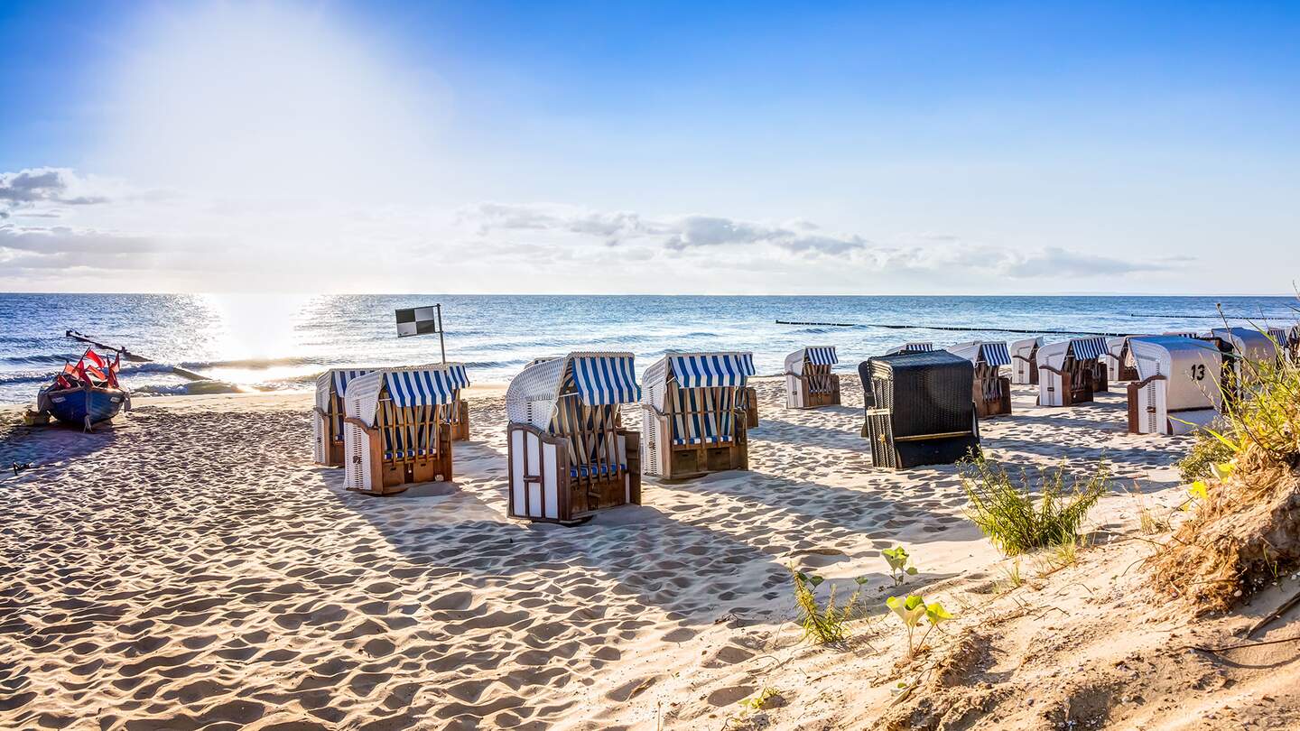  einen Sandstrand mit mehreren traditionellen Strandkoerben, die zum Meer hin ausgerichtet sind | ©  Gettyimages.com/mije_shots
