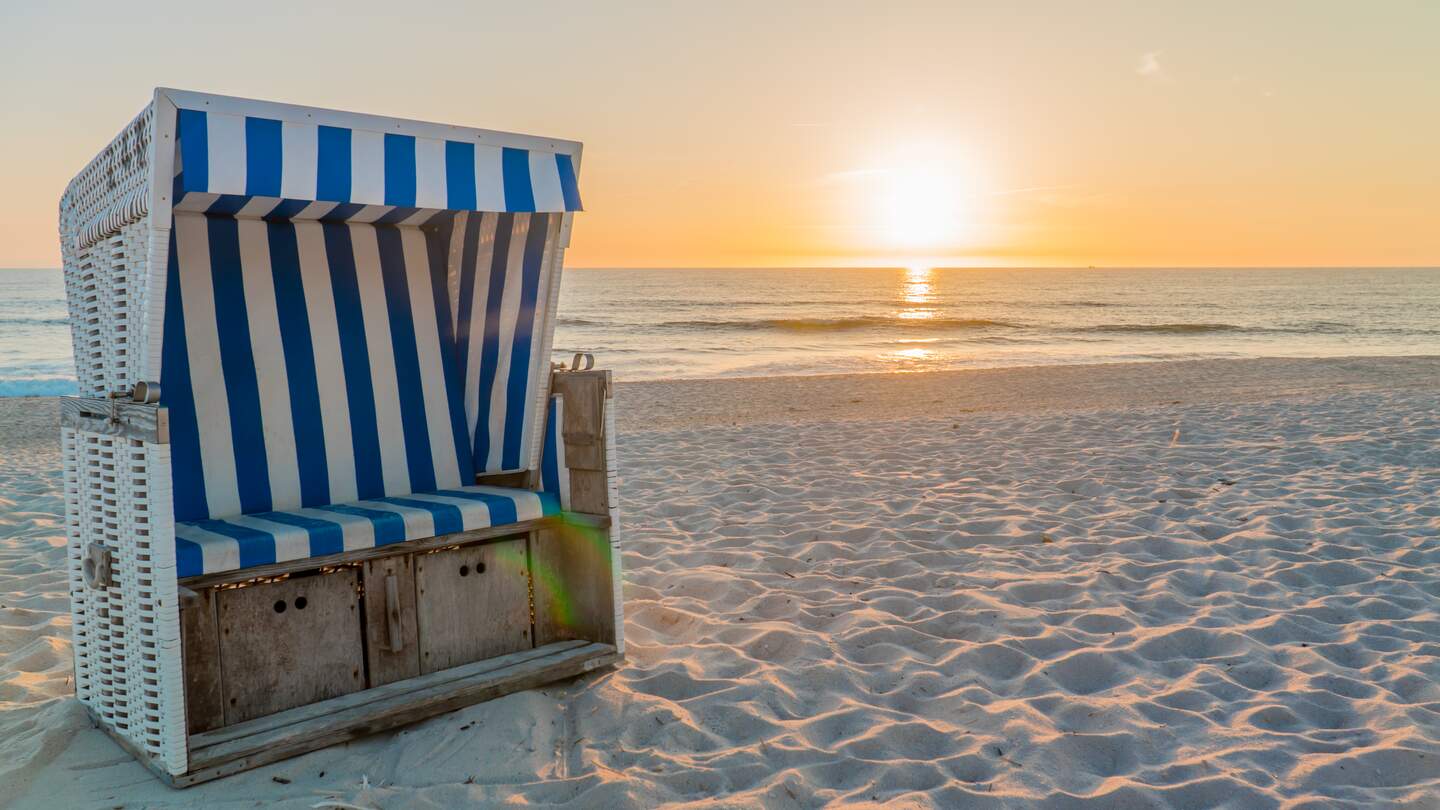 Blau-weiss gestreifter Strandkorb bei Sonnenuntergang auf Sylt | © Gettyimages.com/undefined undefined