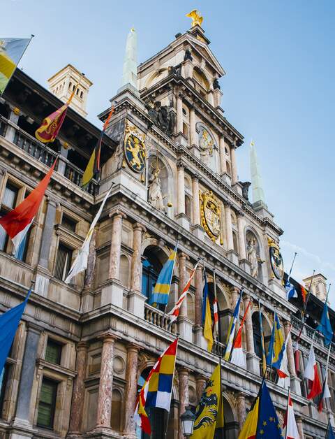 Blick ueber die historische, geflaggte Fassade des Rathauses von Antwerpen gen blauem Himmel in Antwerpen, Flandern/Belgien | © Gettyimages.com/MarioGuti