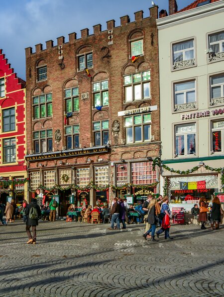 Gebaeude im mittelalterlichen Stil in der Naehe des Marktplatzes (Grote Markt) in Bruecke Menschen flanieren auf dem Platz. | © Gettyimages.com/HIT1912