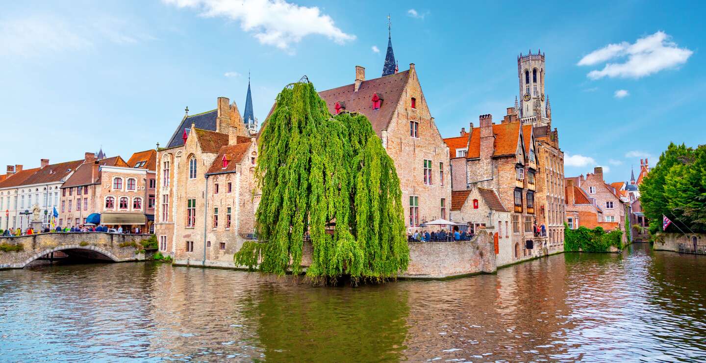 Am Rosenkranz-Quai in Brügge stehen Touristen. Im Hintergrund ist der Belfried. | © Gettyimages.com/adisa