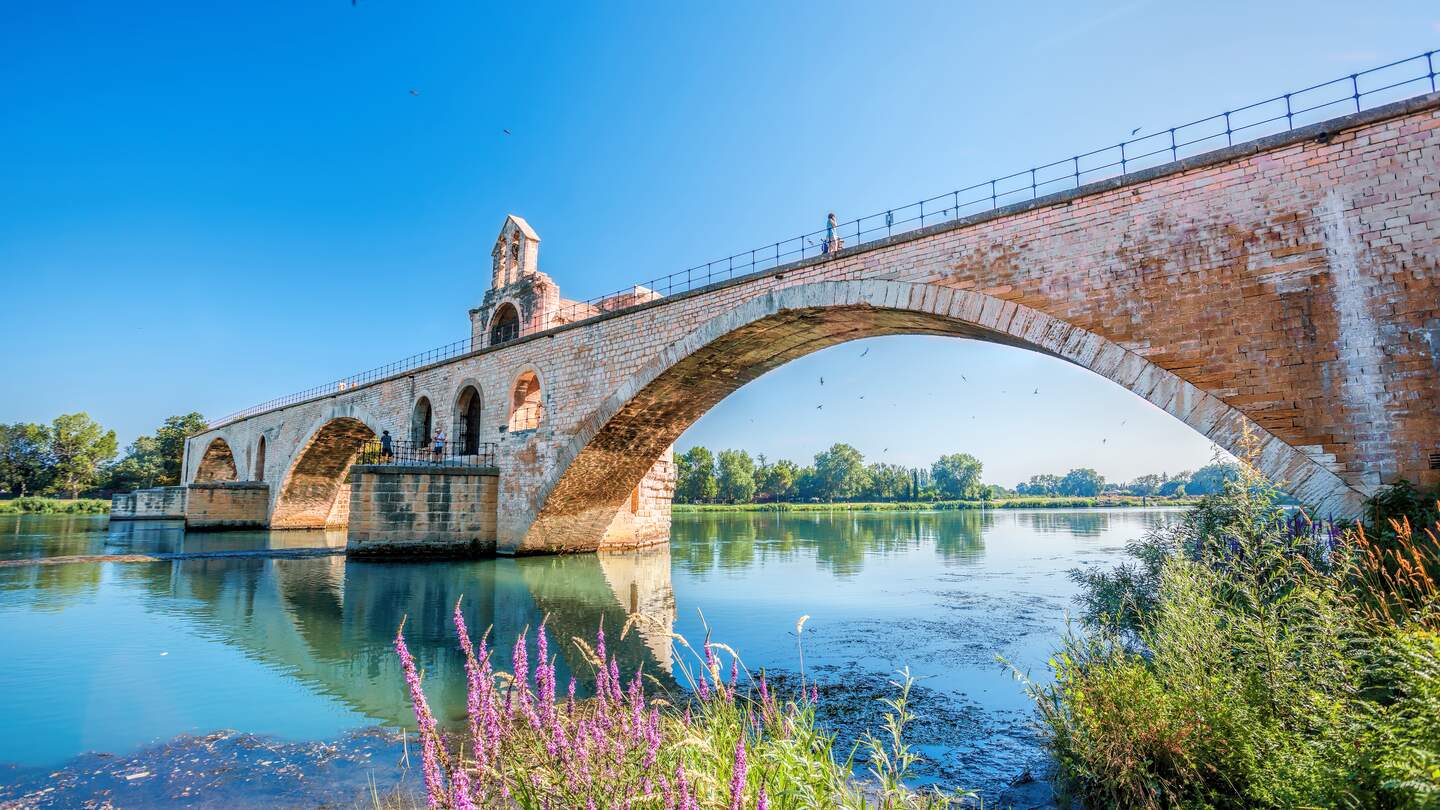 Untersicht auf eine alte Bruecke von Avignon ueber der Rhone mit strahlender Sonne | © Gettyimages.com/extravagantni