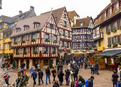 Menschenmenge auf dem Weihnachtsmarkt mit traditionellen Fachwerkhaeusern in der Altstadt von Colmar | © Gettyimages.com/SimonSkafar
