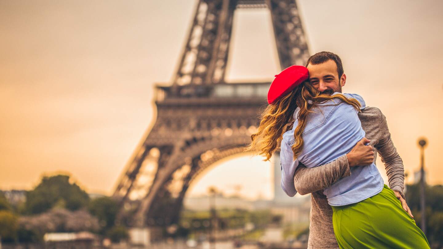 Junges Paris, die ihre Liebe vor dem Eiffelturm in Paris teilen  | © Gettyimages.com/AleksandarNakic