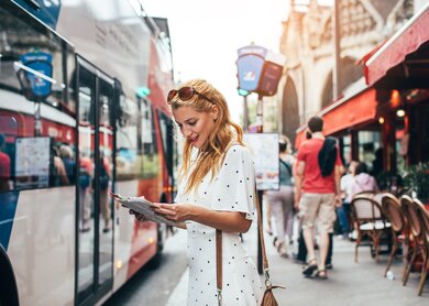 Schöne, junge Frau in Paris macht eine Bustour, eine Stadtkarte in der Hand haltend  | © Gettyimages.com/Jasmina007